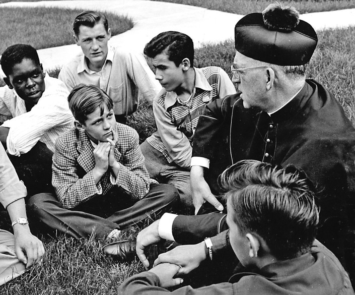 Father Edward Flanagan, the Irish-born priest who founded Boys Town in Nebraska, talks with a group of boys in this undated photo. On March 17, 2015, three years to the day his sainthood cause was officially opened, the Archdiocese of Omaha, Neb., will submit all documentation gathered for his cause to the Vatican. During a Sept. 15 presentation at the Great Hall on the Boys Town campus, Steve Wolf, president of the Father Flanagan League Society of Devotion, said the process was moving at "lightning speed." (CNS photo/courtesy Boys Town)